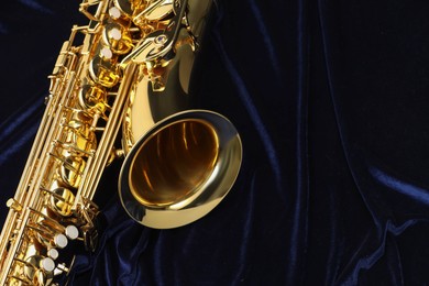 Photo of Jazz. One beautiful saxophone on dark blue fabric, top view. Space for text