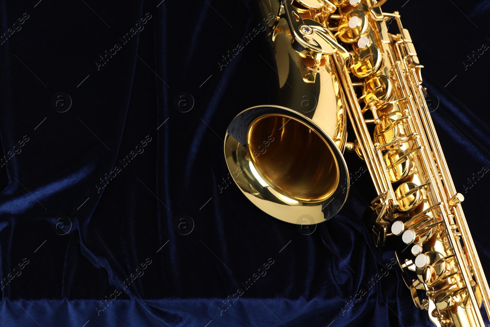 Photo of Jazz. One beautiful saxophone on dark blue fabric, top view. Space for text