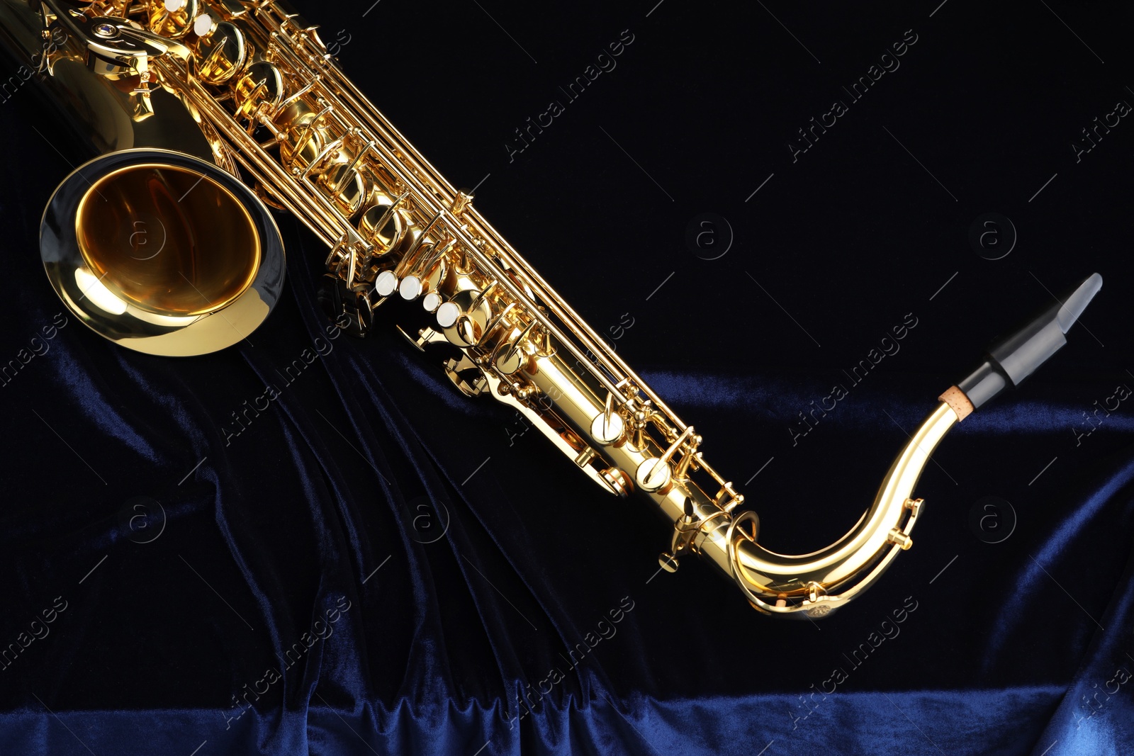 Photo of Jazz. One beautiful saxophone on dark blue fabric, top view