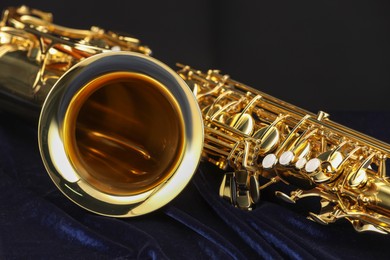 Photo of Jazz. One beautiful saxophone on dark blue fabric against black background, closeup