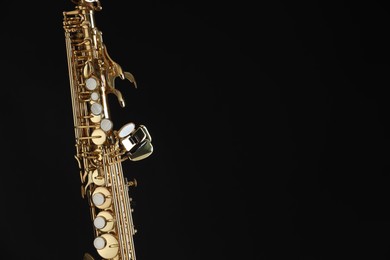 Photo of Jazz. One beautiful saxophone on black background, closeup. Space for text