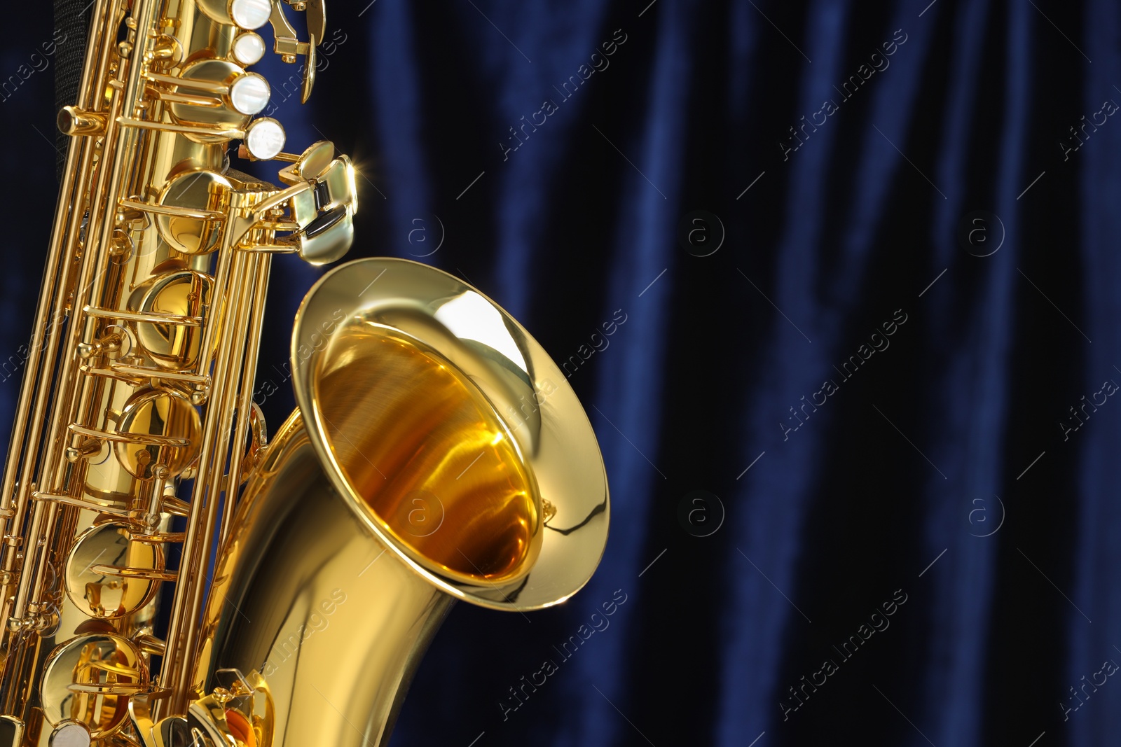 Photo of Jazz. One beautiful saxophone on dark blue background, closeup. Space for text