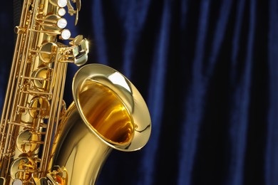 Photo of Jazz. One beautiful saxophone on dark blue background, closeup. Space for text