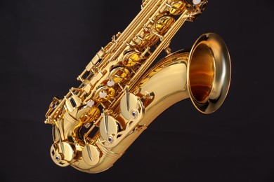 Photo of Jazz. One beautiful saxophone on black background, closeup