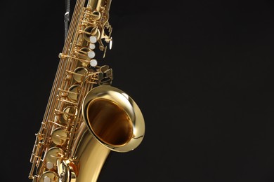 Photo of Jazz. One beautiful saxophone on black background, closeup. Space for text