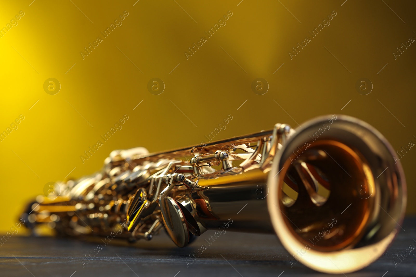 Photo of Jazz. One beautiful saxophone on black table against color background, closeup