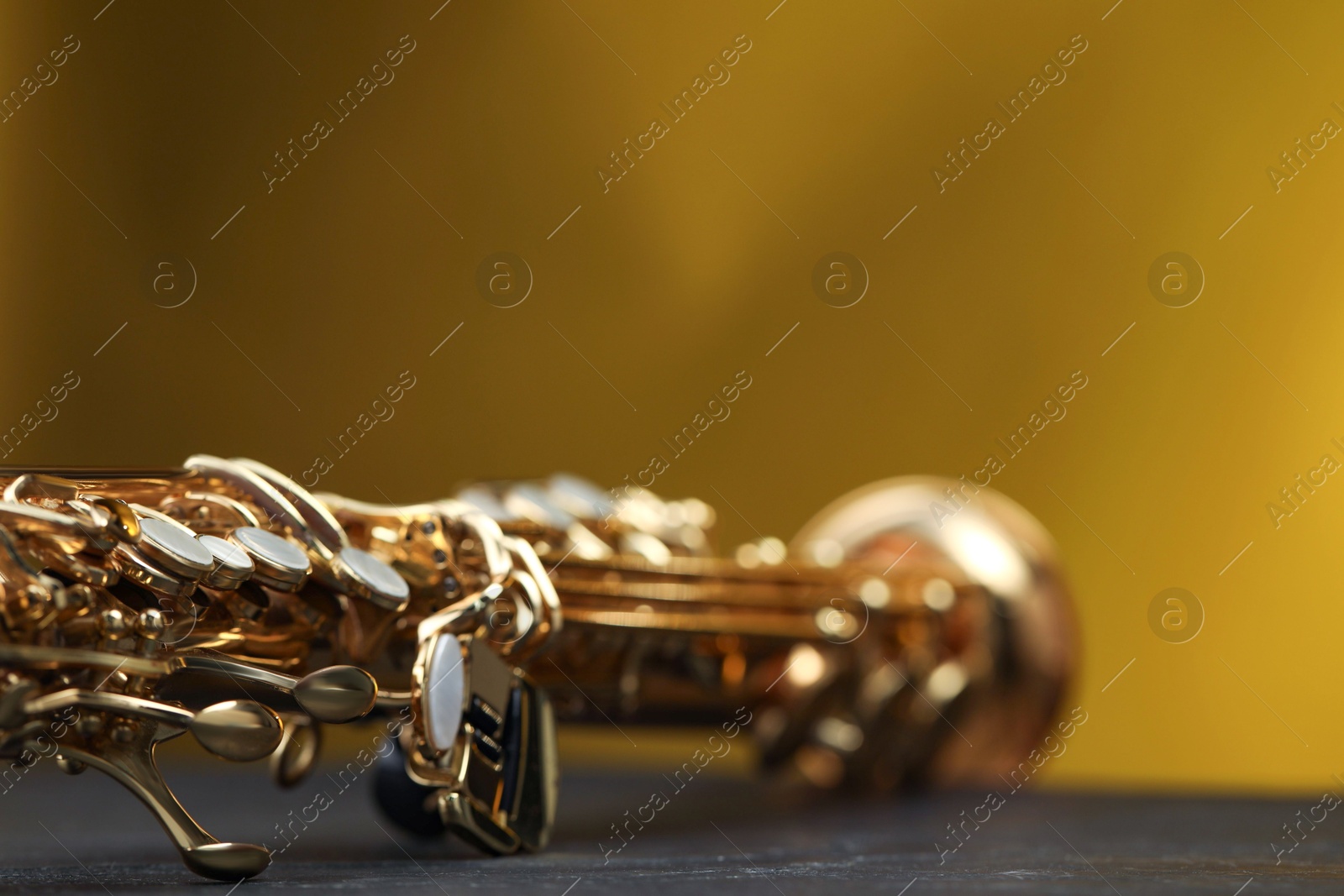 Photo of Jazz. One beautiful saxophone on black table against color background, closeup