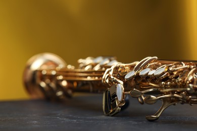 Photo of Jazz. One beautiful saxophone on black table against color background, closeup