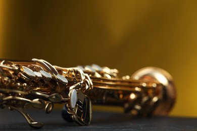 Photo of Jazz. One beautiful saxophone on black table against color background, closeup