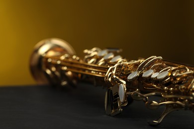 Photo of Jazz. One beautiful saxophone on black table against color background, closeup