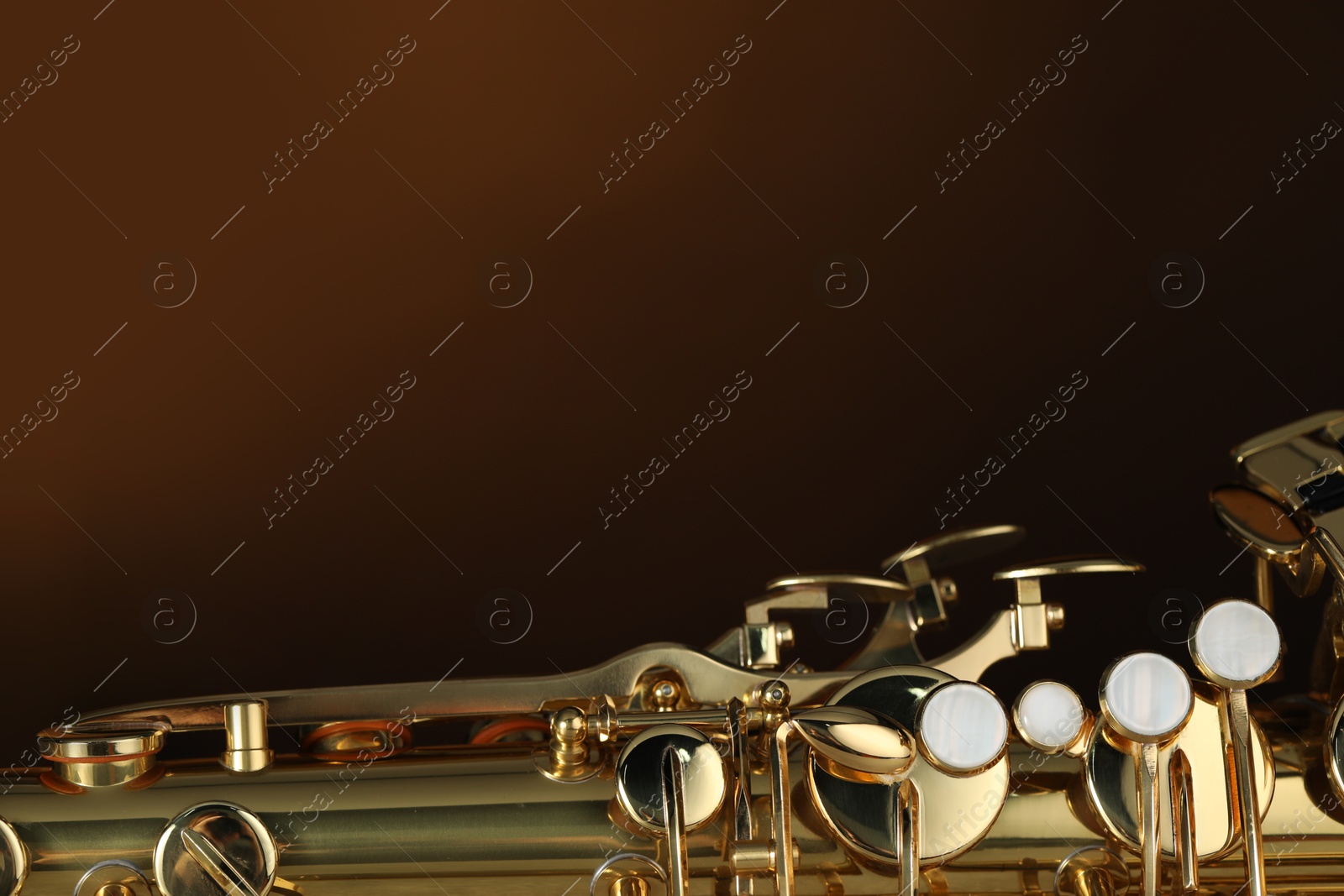 Photo of Jazz. One beautiful saxophone on brown background, closeup. Space for text