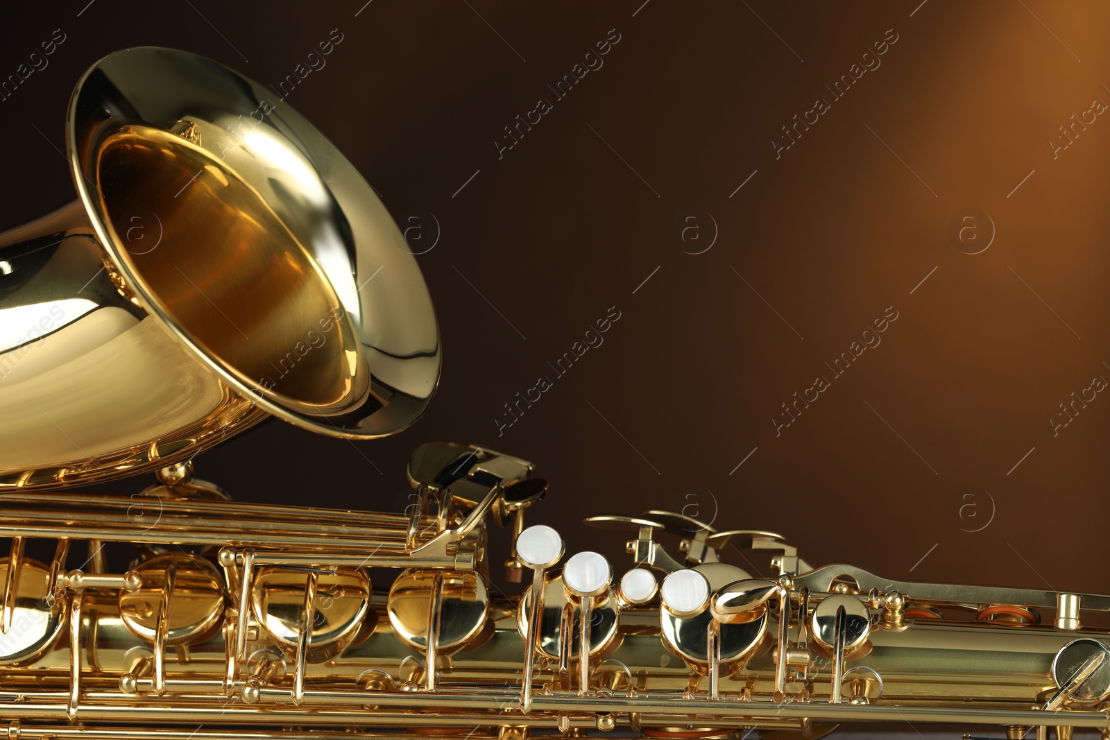 Photo of Jazz. One beautiful saxophone on brown background, closeup. Space for text