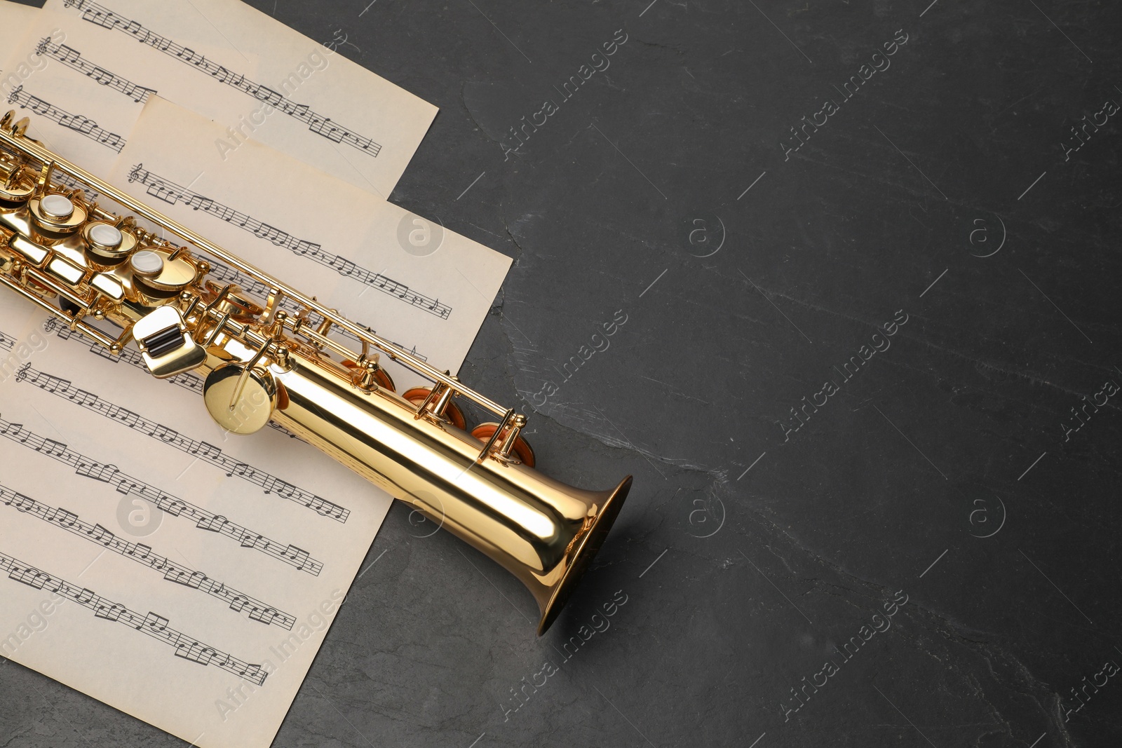 Photo of Jazz. Saxophone and music notes on black table, top view. Space for text