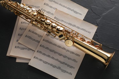 Photo of Jazz. Saxophone and music notes on black table, top view