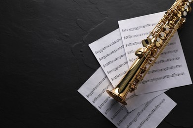 Photo of Jazz. Saxophone and music notes on black table, top view. Space for text