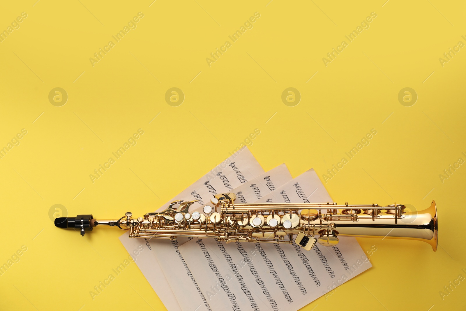 Photo of Jazz. Saxophone and musical notes on yellow background, top view. Space for text