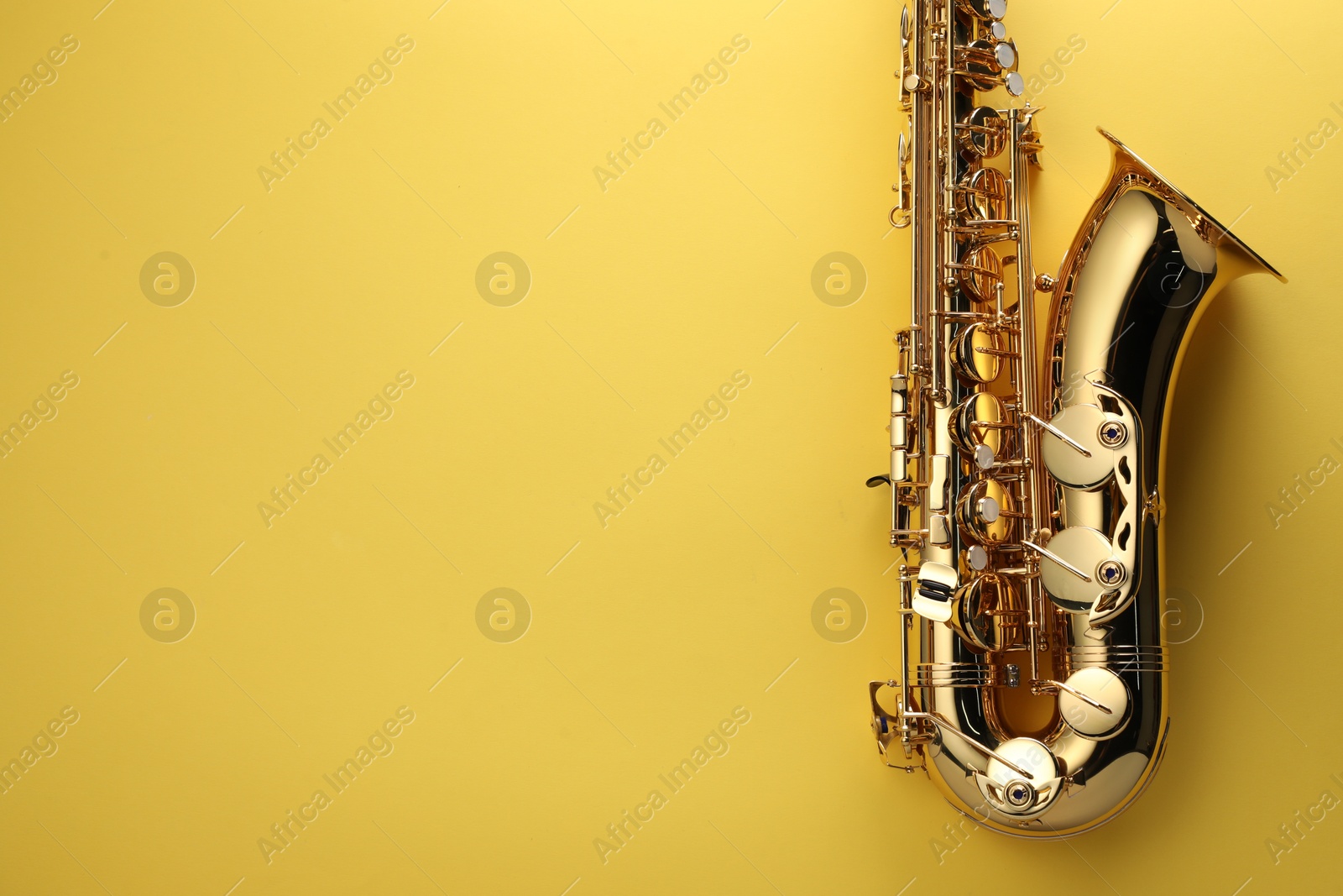 Photo of Jazz. One saxophone on yellow background, top view. Space for text