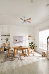 Photo of Stylish room with wooden table, chairs and houseplants. Interior design