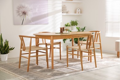 Photo of Stylish room with wooden table, chairs and houseplants. Interior design