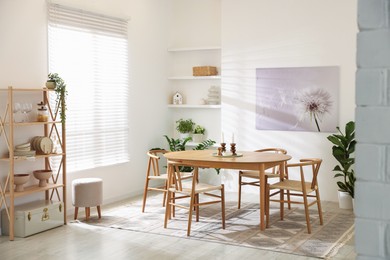 Photo of Stylish room with wooden table, chairs and houseplants. Interior design