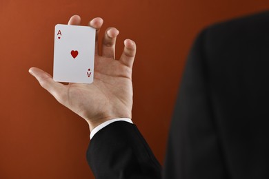 Illusionist showing playing card on dark orange background, closeup