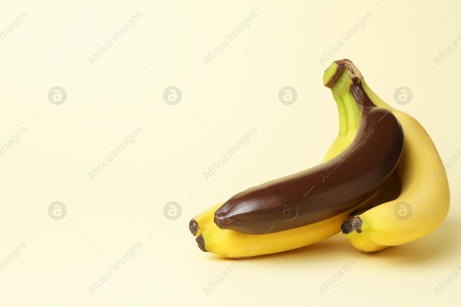 Photo of Stop racism. Bunch of yellow bananas with dark one on beige background, space for text