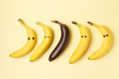 Photo of Stop racism. One dark banana among yellow ones on beige background, flat lay