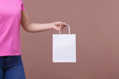 Photo of Woman with blank shopping bag on dark beige background, closeup. Mockup for design