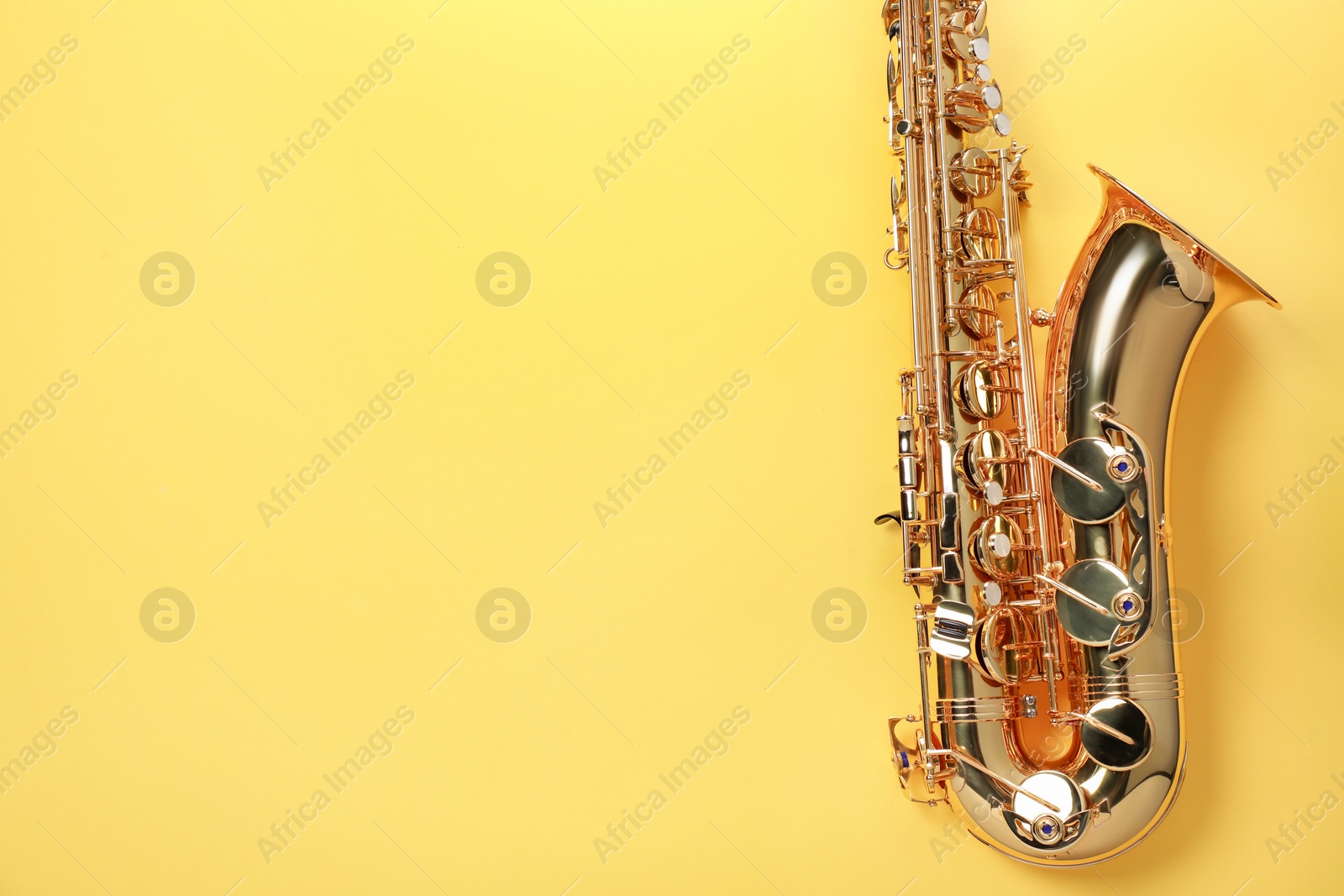 Photo of Jazz. One saxophone on yellow background, top view. Space for text