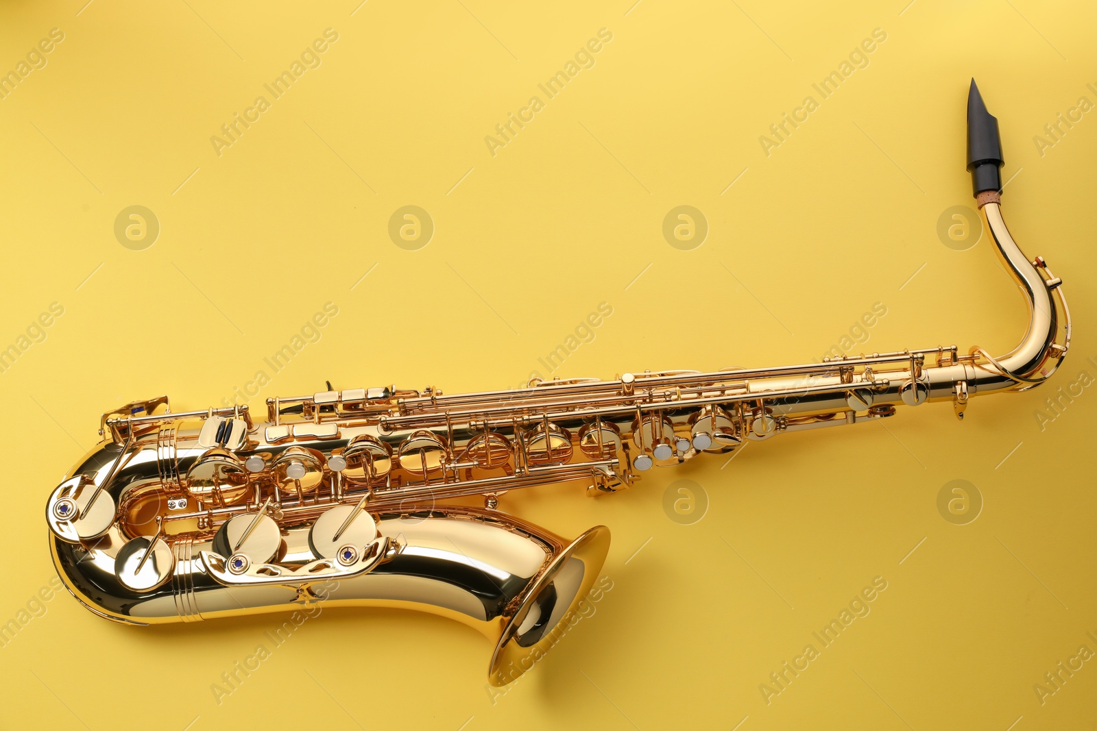 Photo of Jazz. One saxophone on yellow background, top view. Space for text