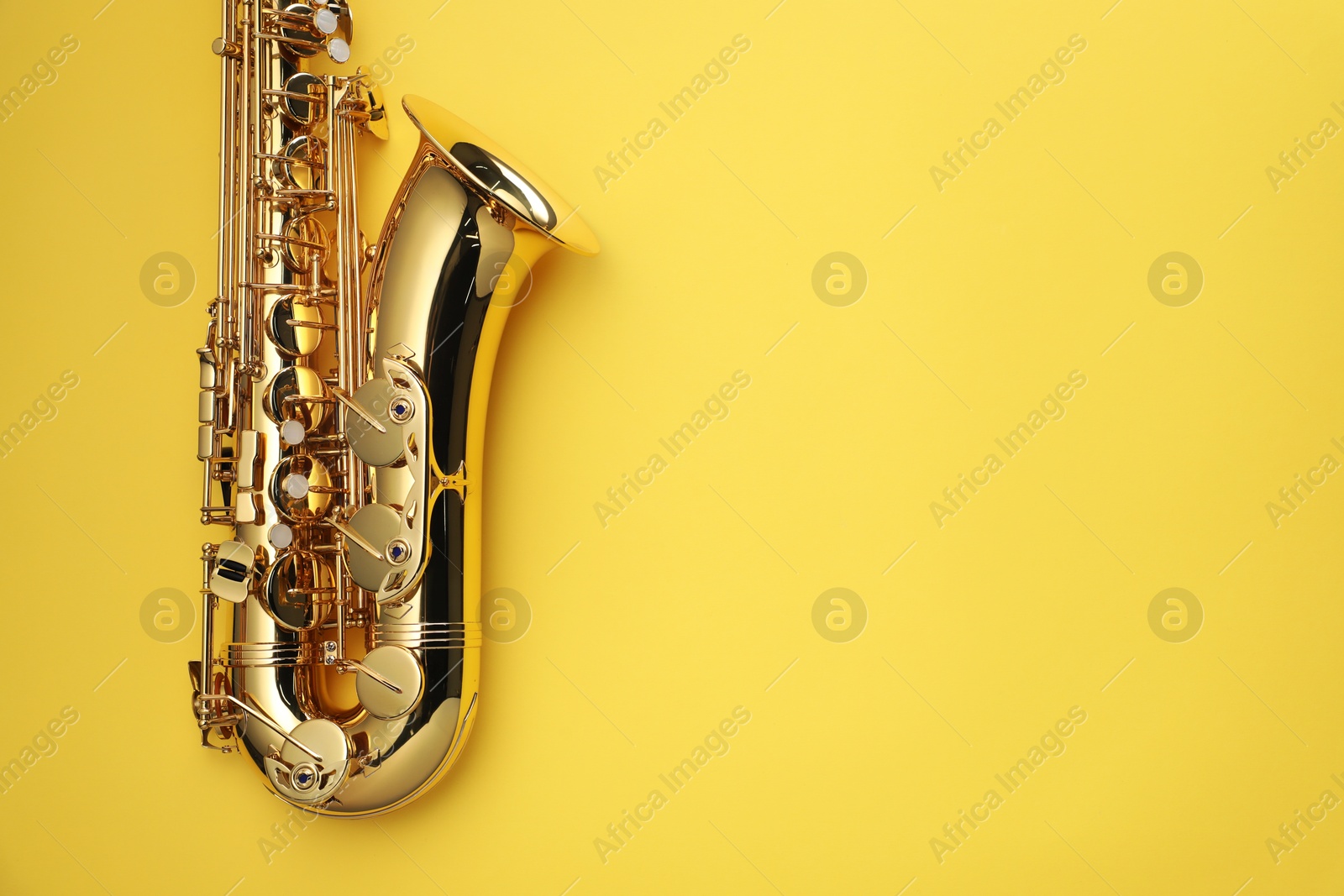 Photo of Jazz. One saxophone on yellow background, top view. Space for text