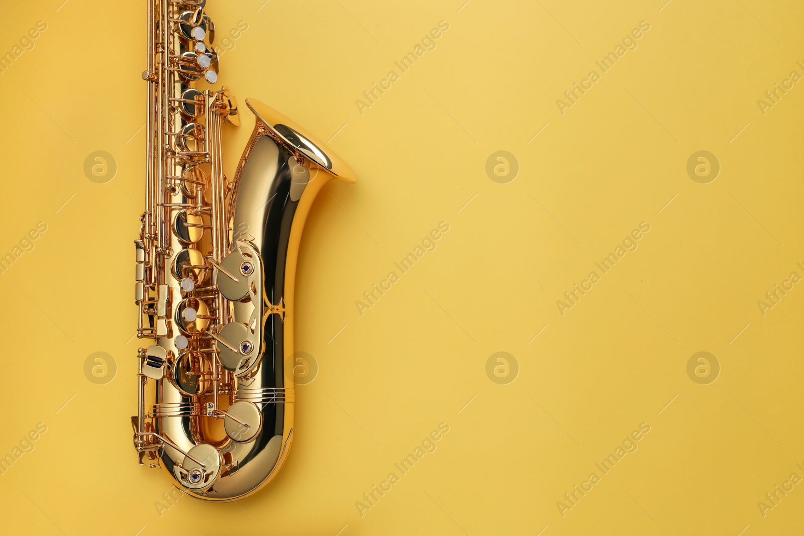 Photo of Jazz. One saxophone on yellow background, top view. Space for text