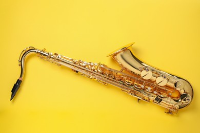 Photo of Jazz. One saxophone on yellow background, top view