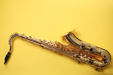 Photo of Jazz. One saxophone on yellow background, top view