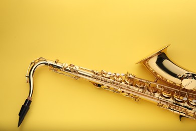 Photo of Jazz. One saxophone on yellow background, top view