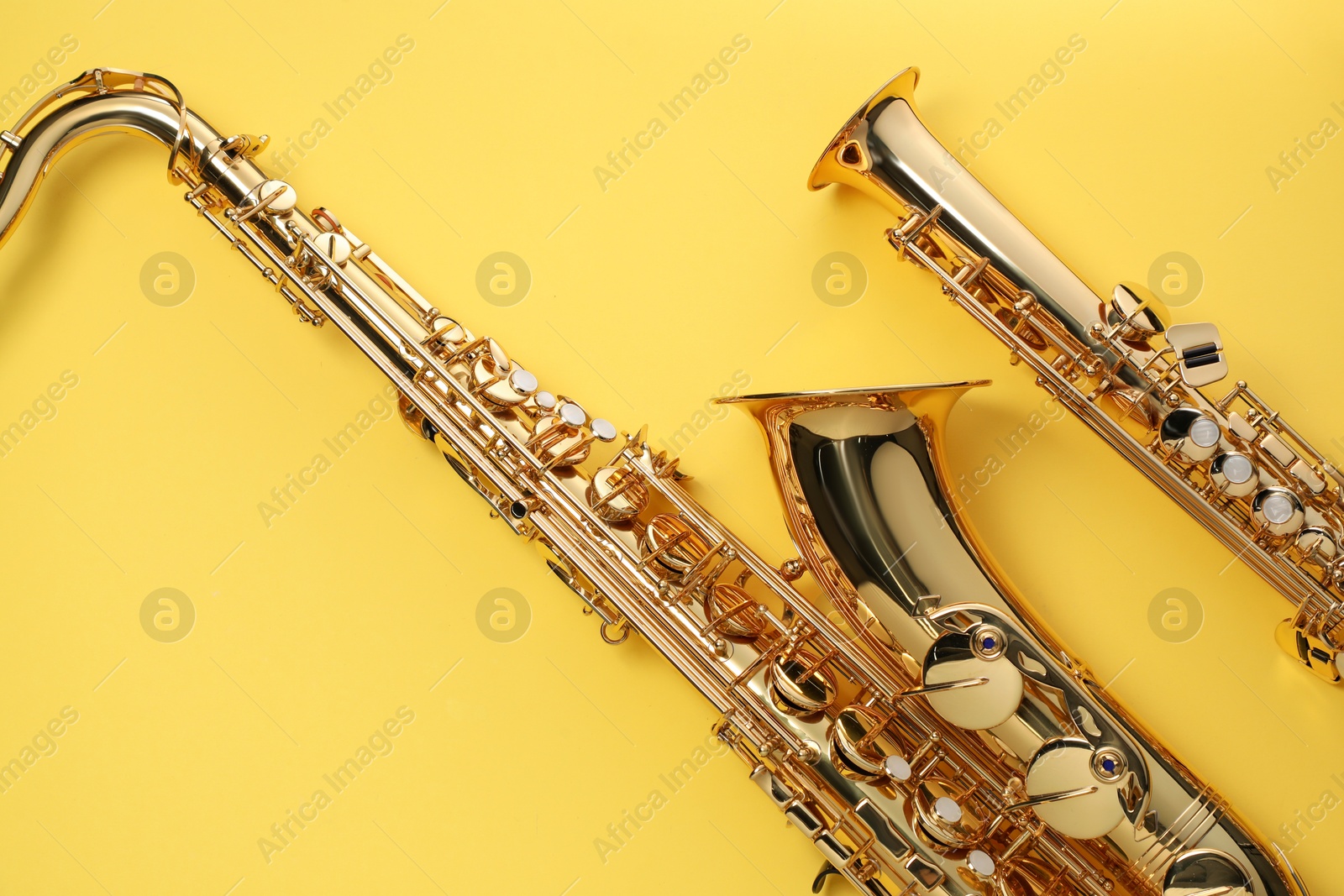 Photo of Jazz. Shiny saxophones on yellow background, top view