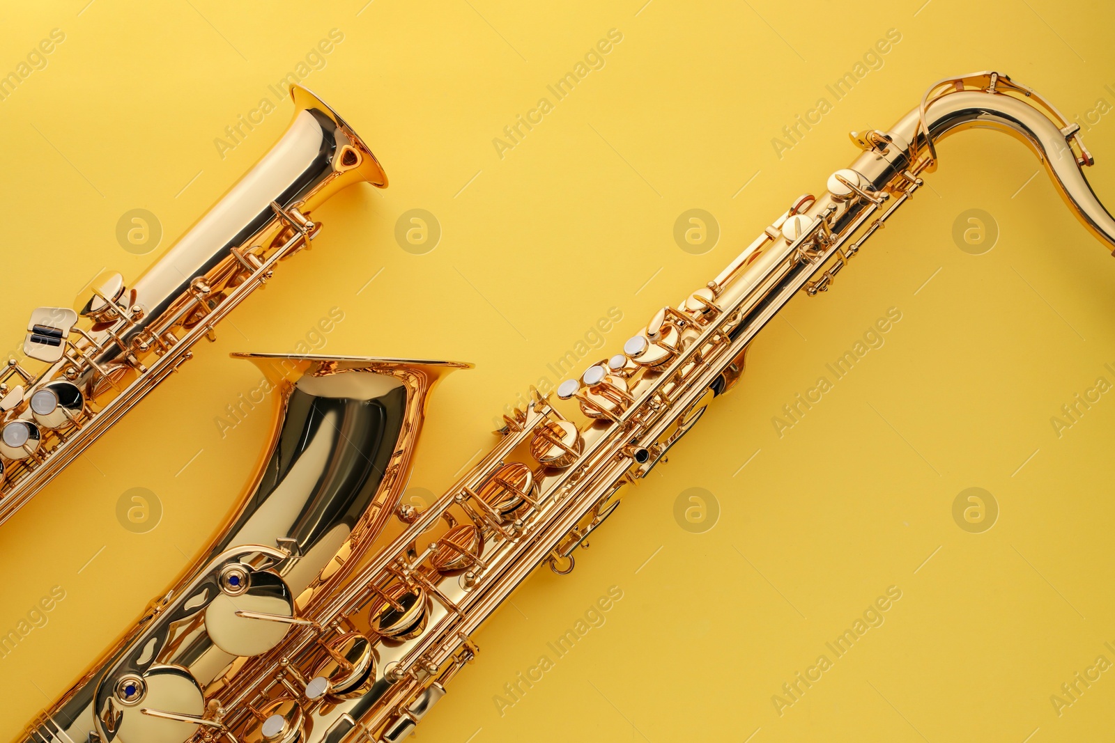 Photo of Jazz. Shiny saxophones on yellow background, top view