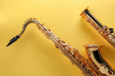 Photo of Jazz. Shiny saxophones on yellow background, top view