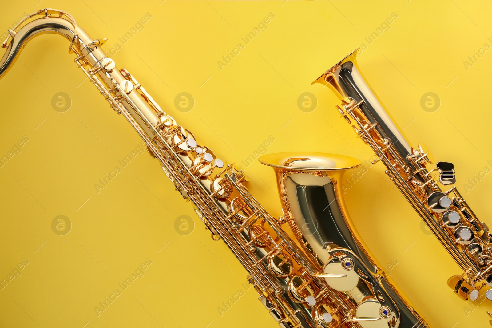 Photo of Jazz. Shiny saxophones on yellow background, top view