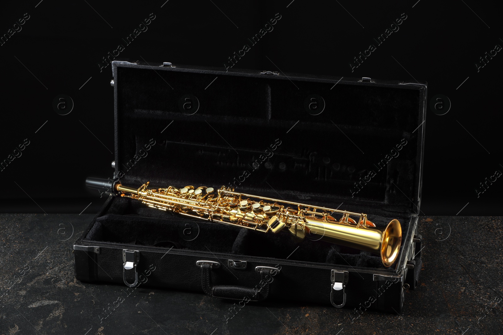 Photo of Jazz. Golden saxophone in case on black textured table