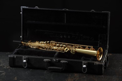 Photo of Jazz. Golden saxophone in case on black textured table