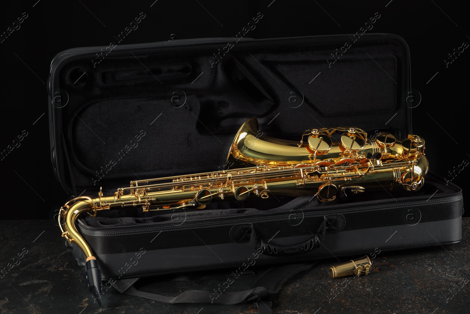 Photo of Jazz. Golden saxophone in case on black textured table