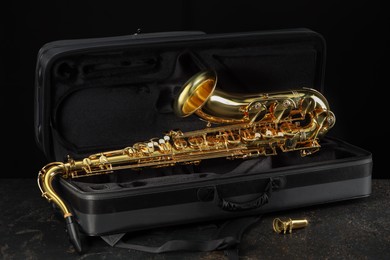 Photo of Jazz. Golden saxophone in case on black textured table