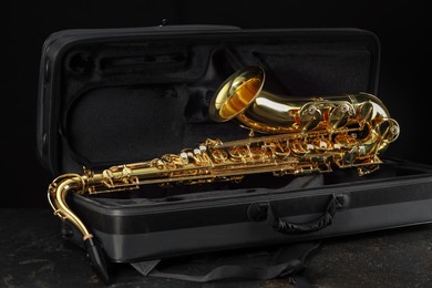 Photo of Jazz. Golden saxophone in case on black textured table