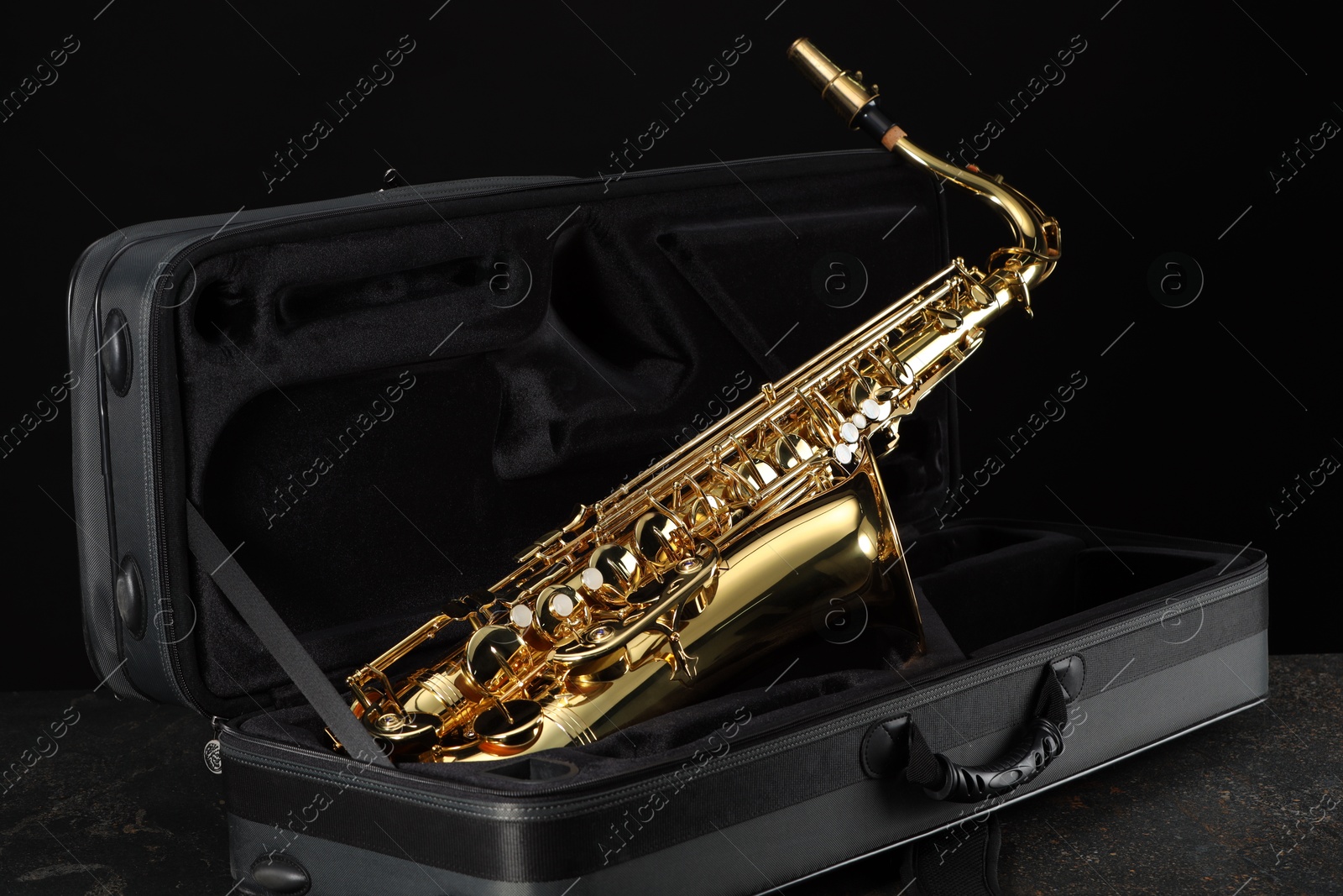 Photo of Jazz. Golden saxophone in case on black textured table