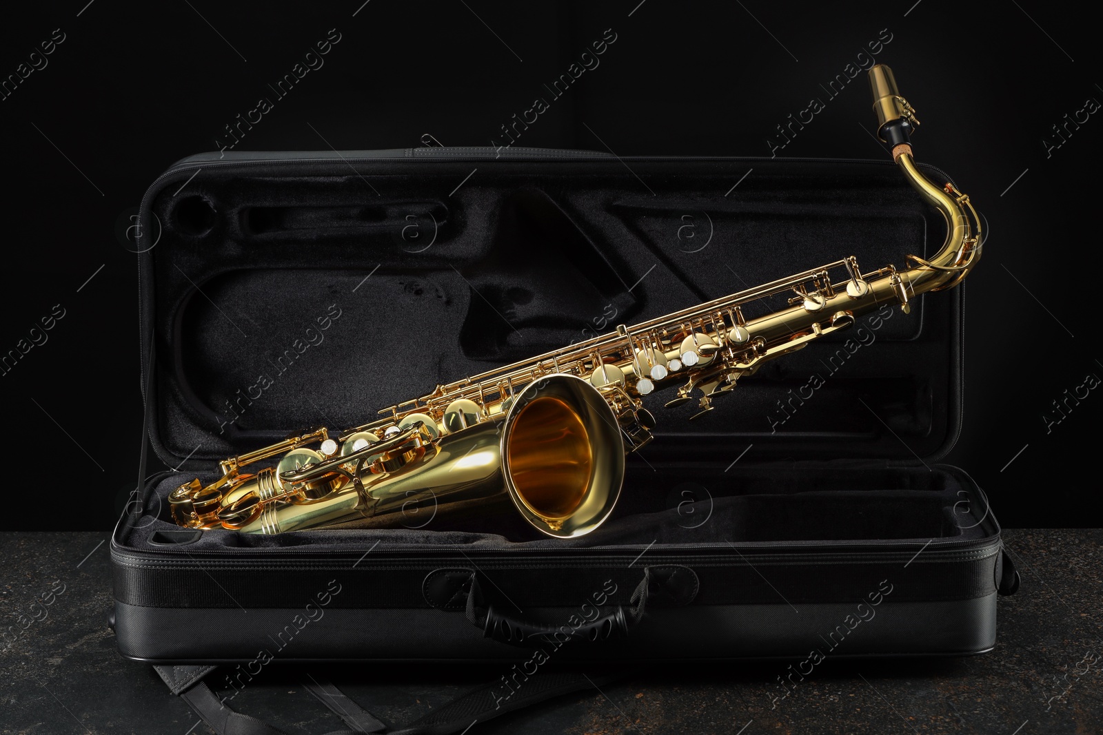 Photo of Jazz. Golden saxophone in case on black textured table