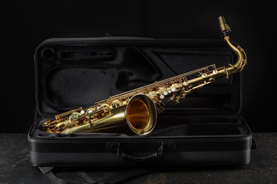 Photo of Jazz. Golden saxophone in case on black textured table