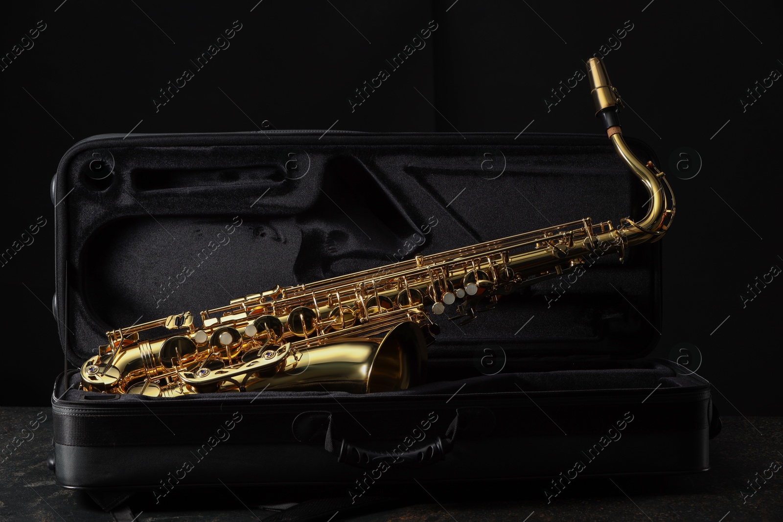 Photo of Jazz. Golden saxophone in case on black textured table