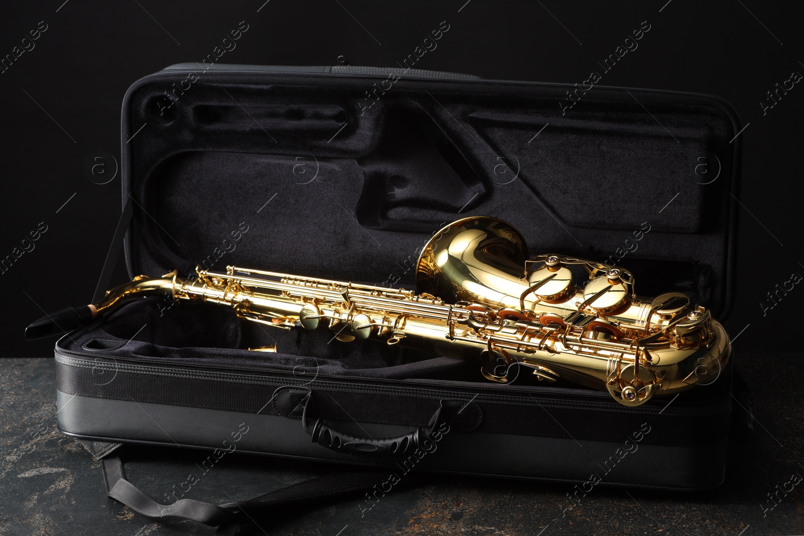 Photo of Jazz. Golden saxophone in case on black textured table