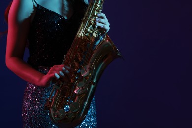 Photo of Professional musician playing saxophone on color background, closeup. Space for text